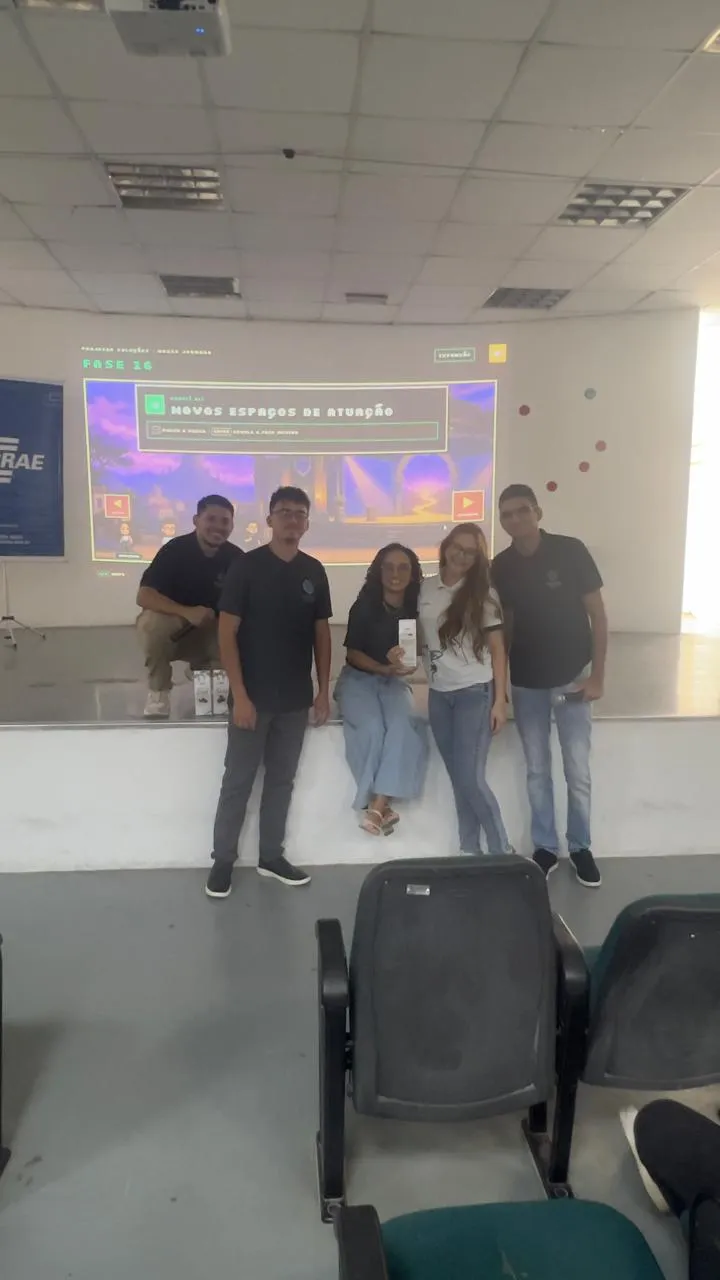 Equipe da Projetar em um auditório, em frente a um telão